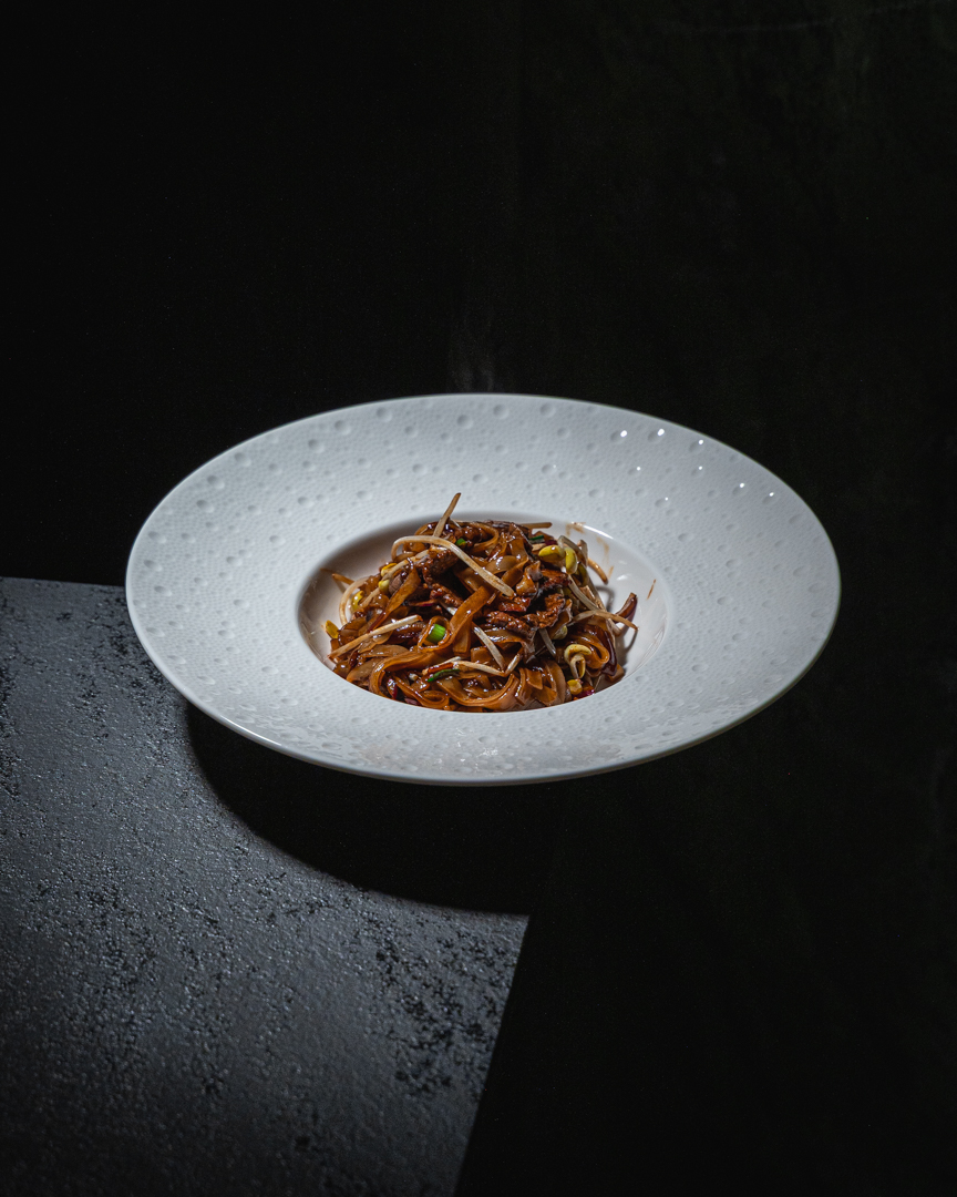 Tagliatelle di riso con filetto di vitello servite su piatto bianco