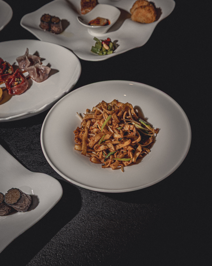 Noodles fatti in casa con verdure, uovo e spezie serviti in ciotola bianca